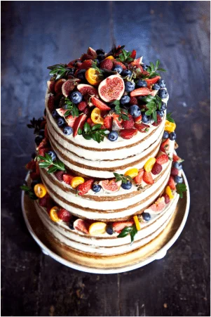 Naked tiered cake topped with figs, berries and citrus